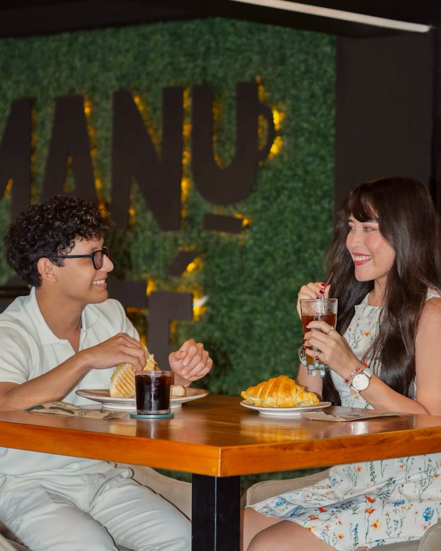 Pareja conversando con croissant y bebidas frías en Manu Café Inmaculada